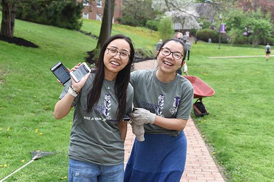 Photo of two international students on 波胆网站's 足球波胆平台, pausing while volunteering to plant flowers